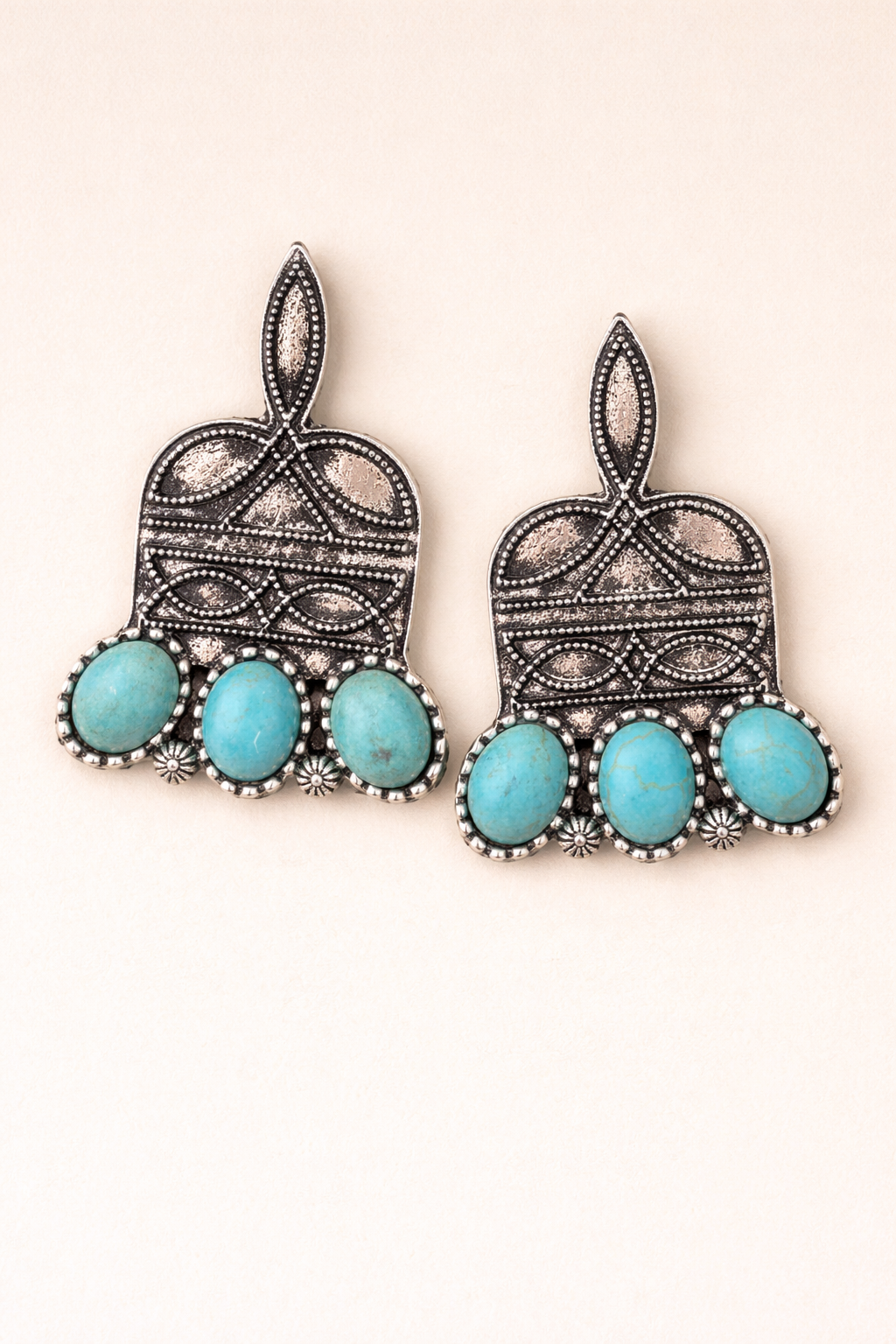 Pair of earrings with boot stitch print and turquoise stones on a beige background