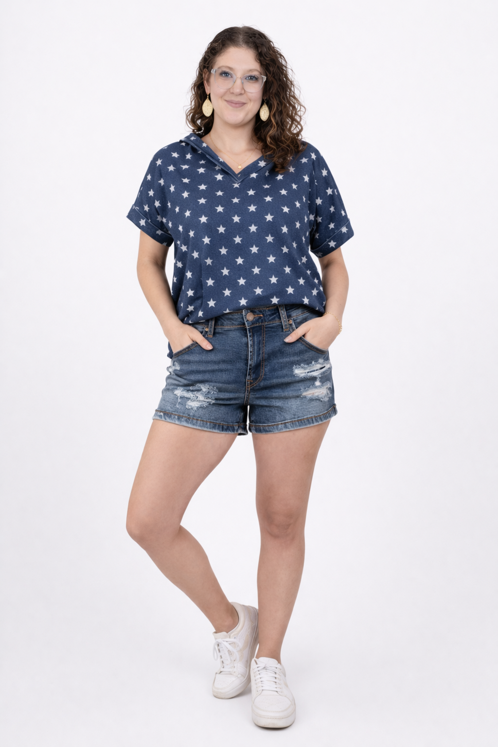 A girl wearing distressed denim shorts and a shirt with stars on it in front of a white background