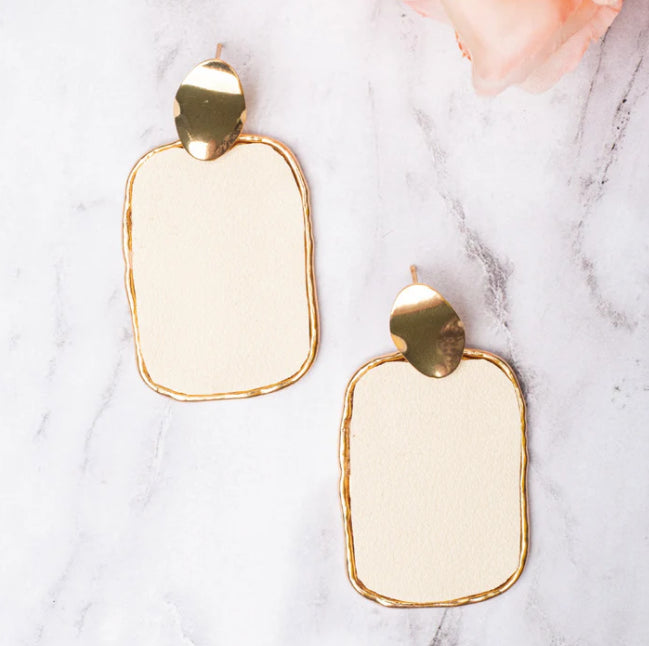 Gold and white earrings on a marble surface