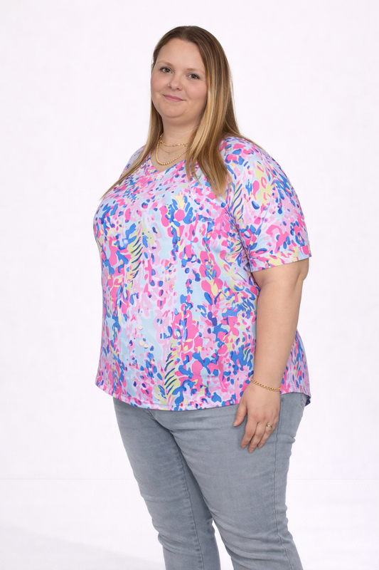 Woman wearing a colorful floral blouse and denim pants on a white background