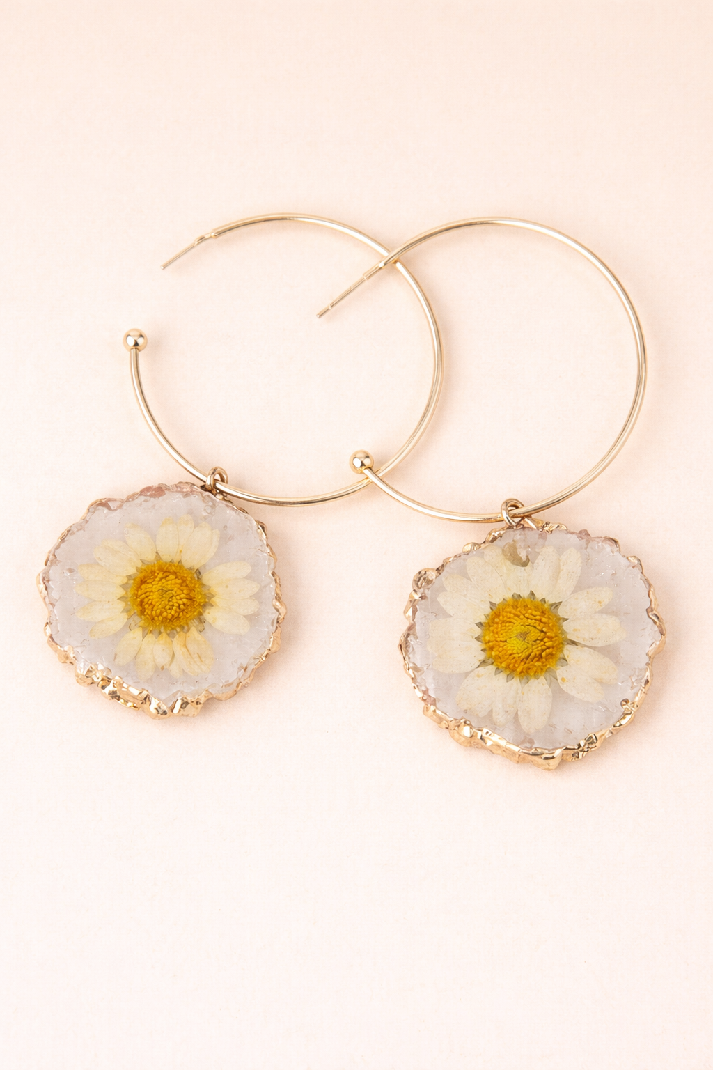 Gold hoop earrings with floral accents on a light background