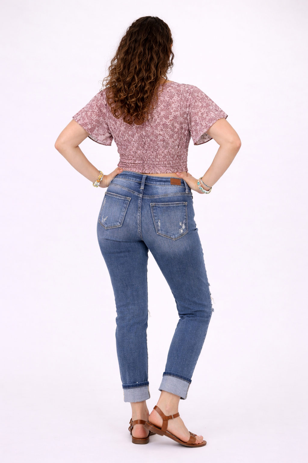 Woman wearing blue jeans and a patterned top on a white background