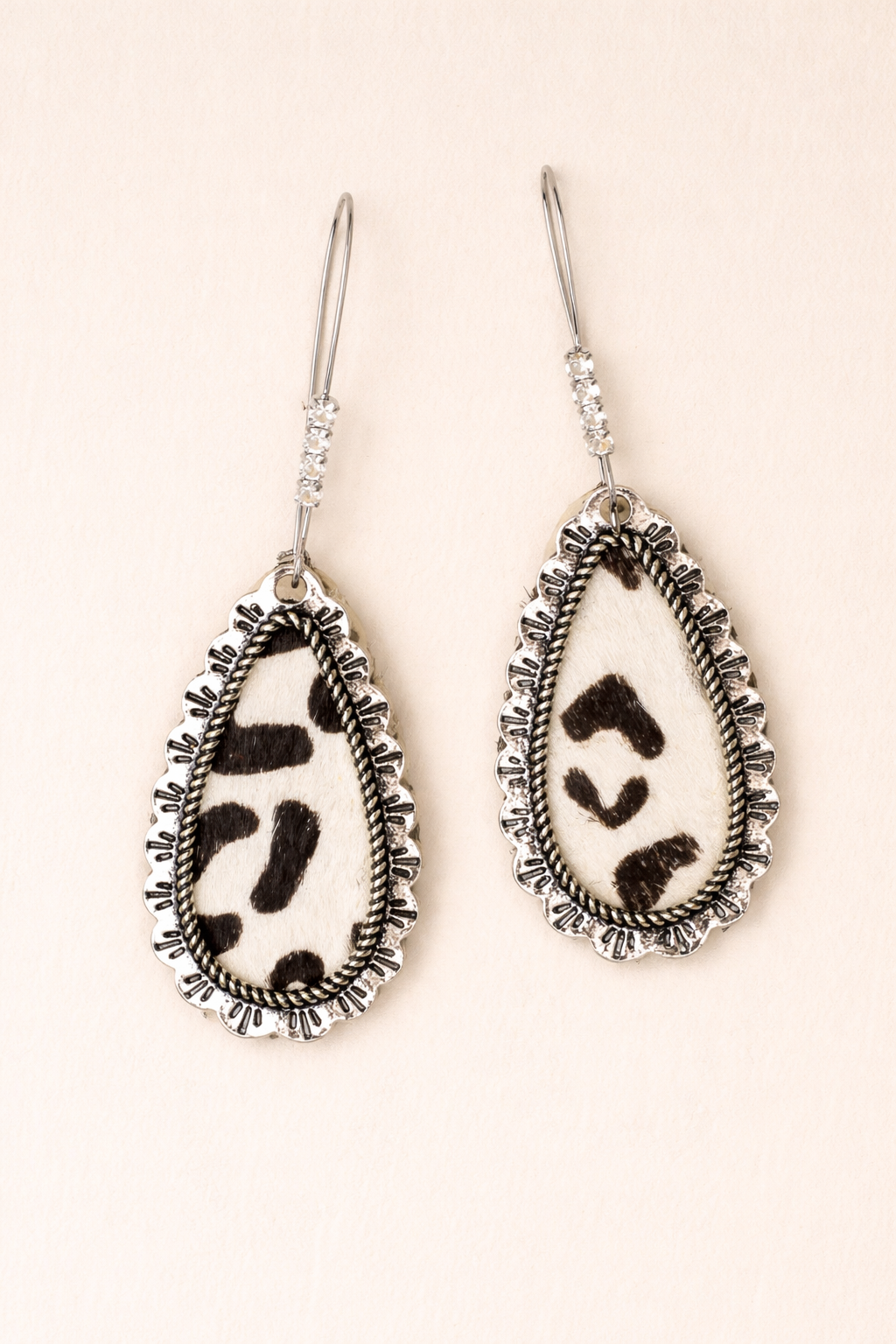 Teardrop-shaped earrings with black and white pattern on a beige background
