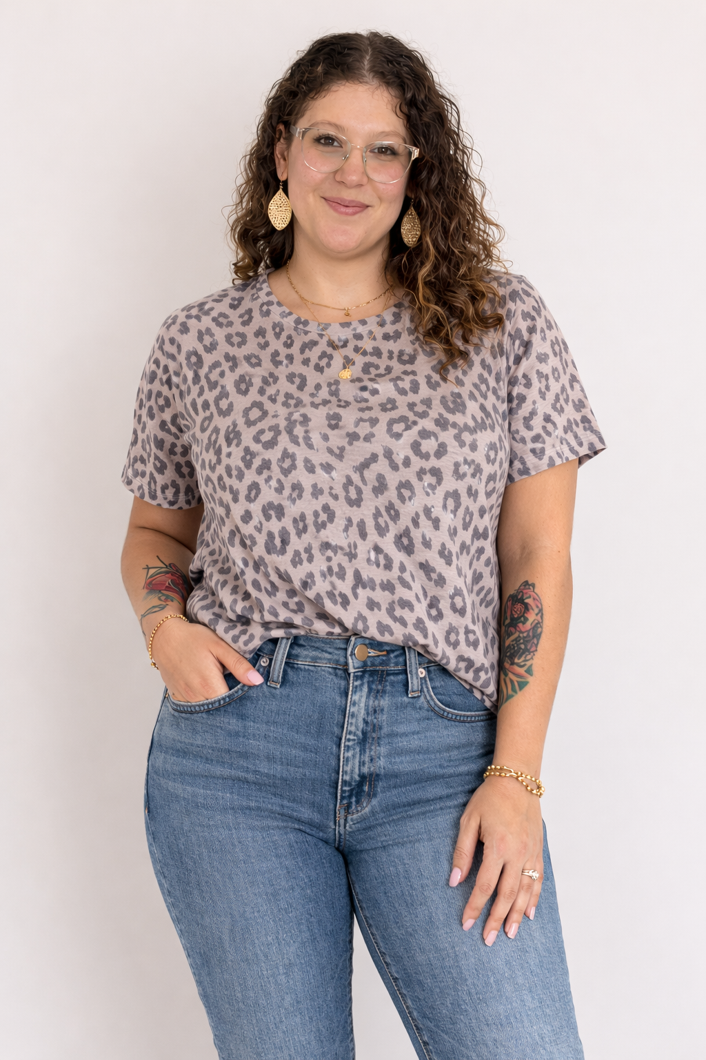 Woman wearing a leopard print shirt and blue jeans against a white background