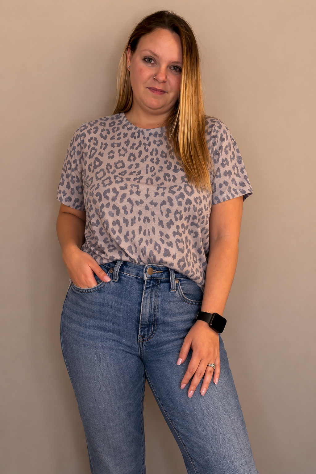Woman wearing a leopard print shirt and blue jeans against a plain background