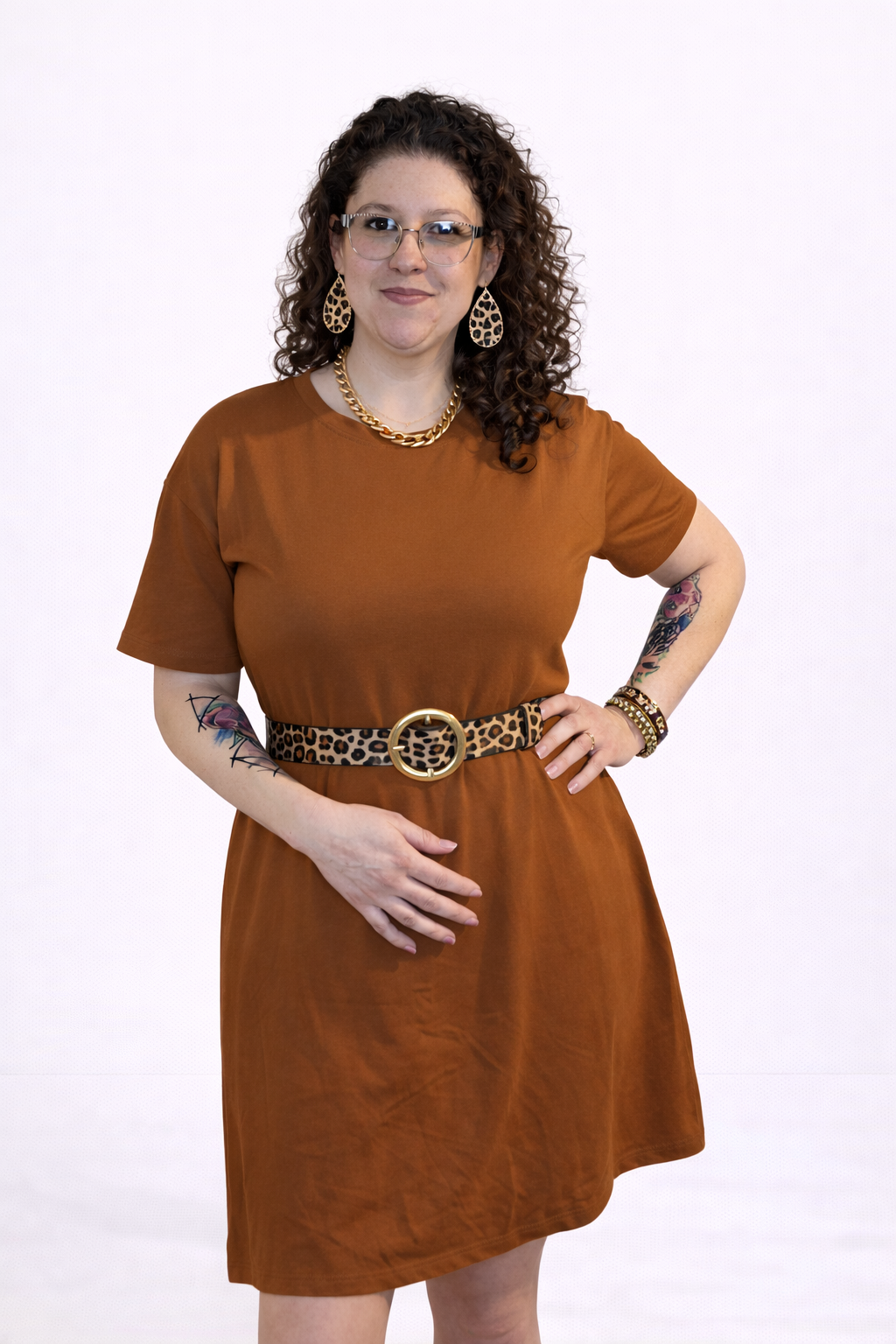 Woman wearing a brown dress with a leopard print belt on a white background