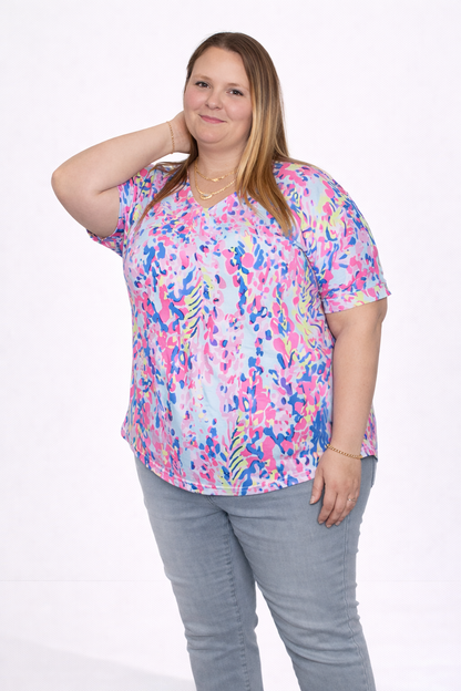 Woman wearing a colorful patterned shirt and denim pants on a white background