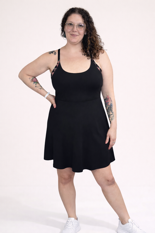 Woman wearing a black dress with aztec print straps on a white background