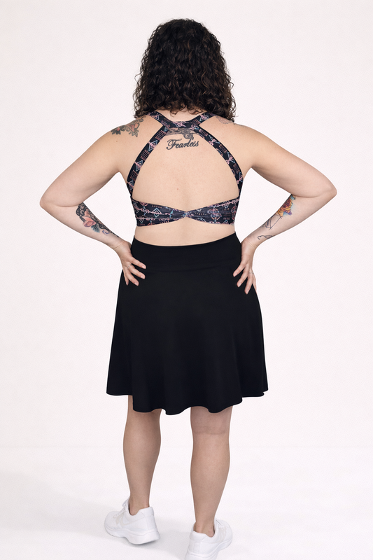 Person wearing a black dress with aztec print straps on a white background