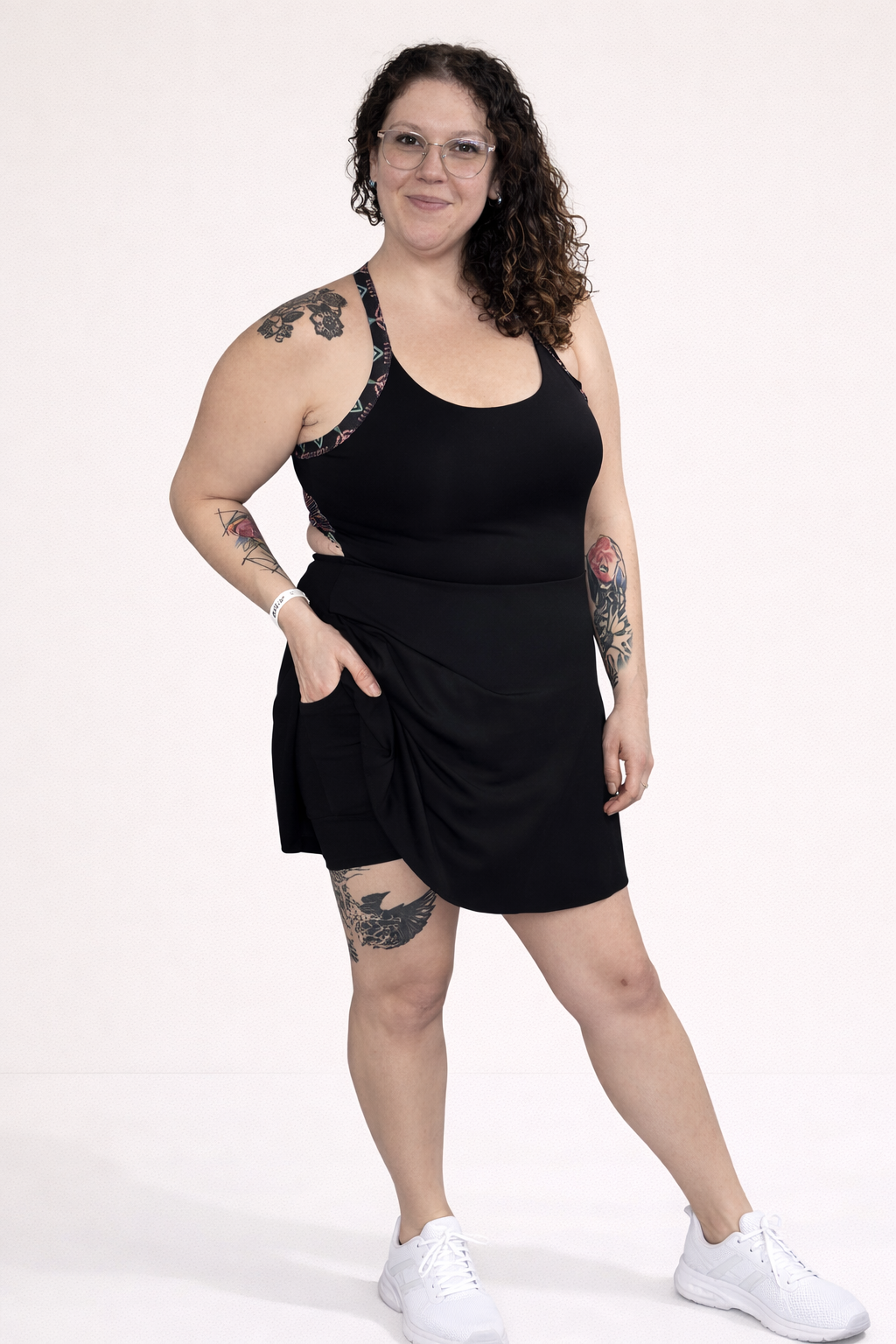 Person wearing a black sleeveless dress with aztec patterns on straps against a white background