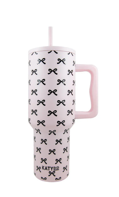 Pink tumbler with black bow pattern and handle on a white background