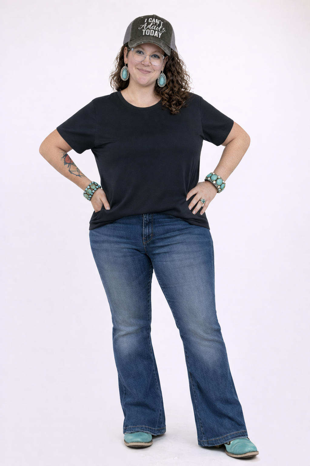 Woman wearing a black t-shirt, blue jeans, and a cap with the words "I can't adult today" on a white background