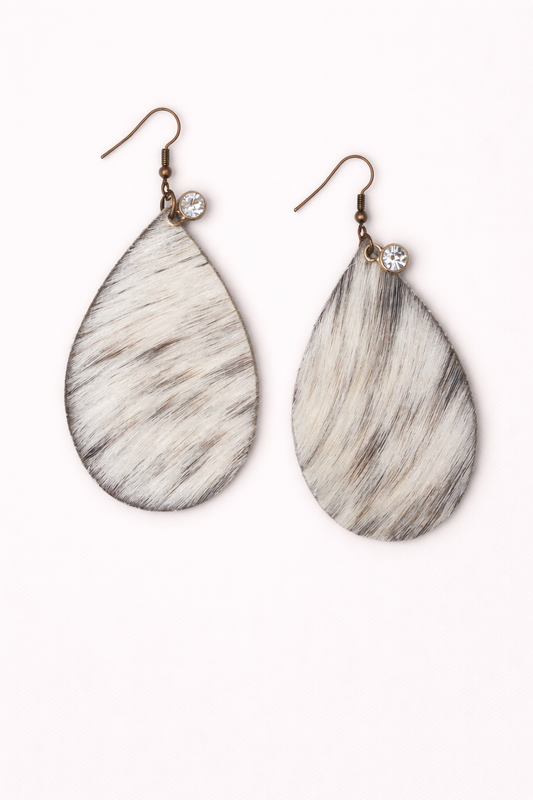 Teardrop-shaped earrings with cowprint fur pattern on a white background