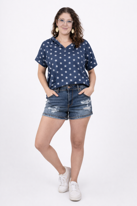 A girl wearing distressed denim shorts and a shirt with stars on it in front of a white background