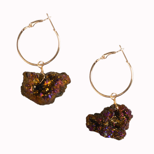 Gold hoop earrings with natural stone drops on a light background.