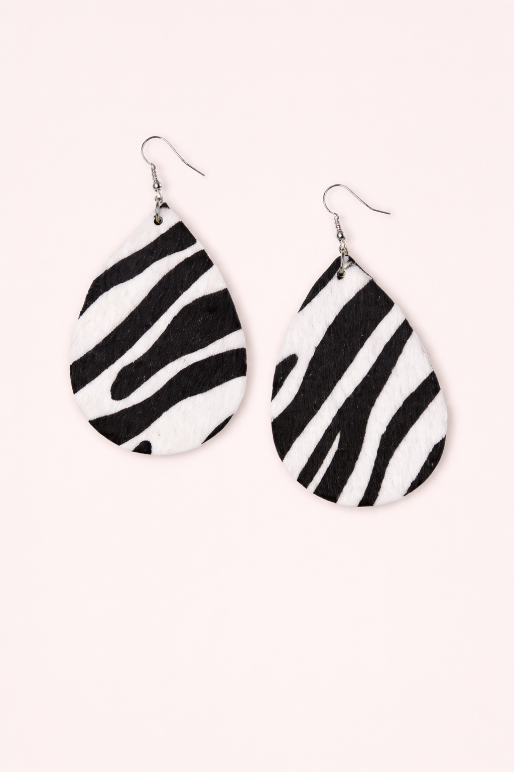 Black and white zebra earrings on a pink background