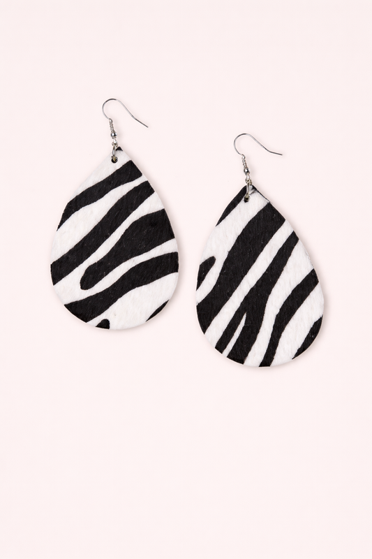 Black and white zebra earrings on a pink background